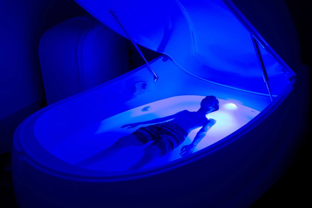 Man floating in float pod with blue lighting
